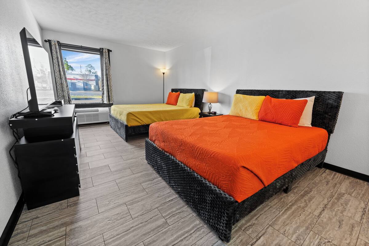 Ein Hotelzimmer mit zwei Betten, einem Schreibtisch und einem Fenster mit Vorhängen.