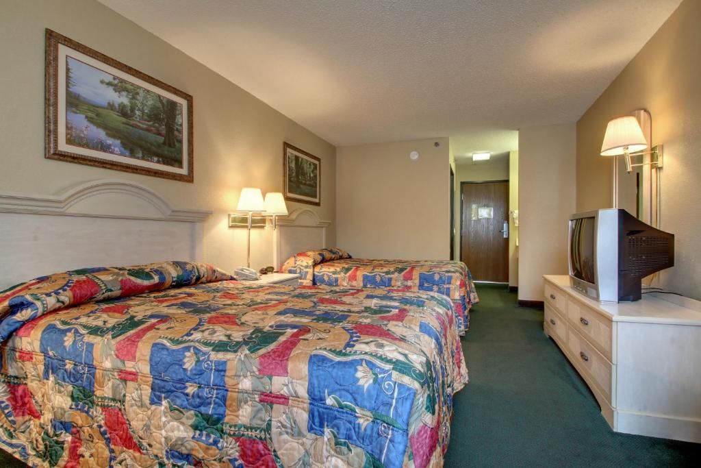 Habitación de hotel con una cama grande, un televisor en una cómoda y un pasillo que conduce a otra habitación.