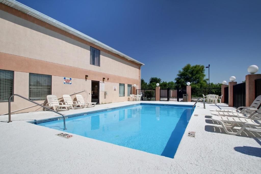 Piscina com espreguiçadeiras e um edifício com fachada bege.