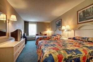 A hotel room with two beds, a dresser, a desk, and a television.