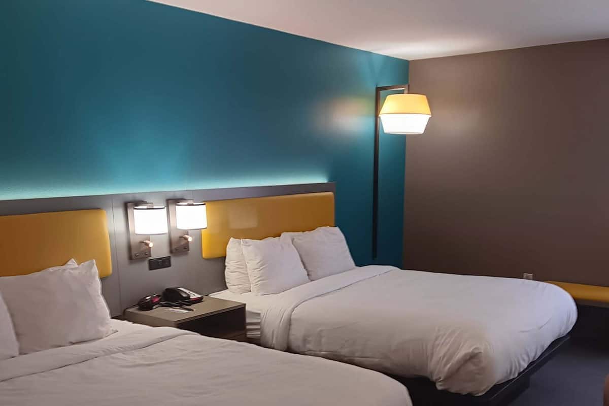 Ein Hotelzimmer mit zwei Betten, einem Nachttisch und einer Lampe.