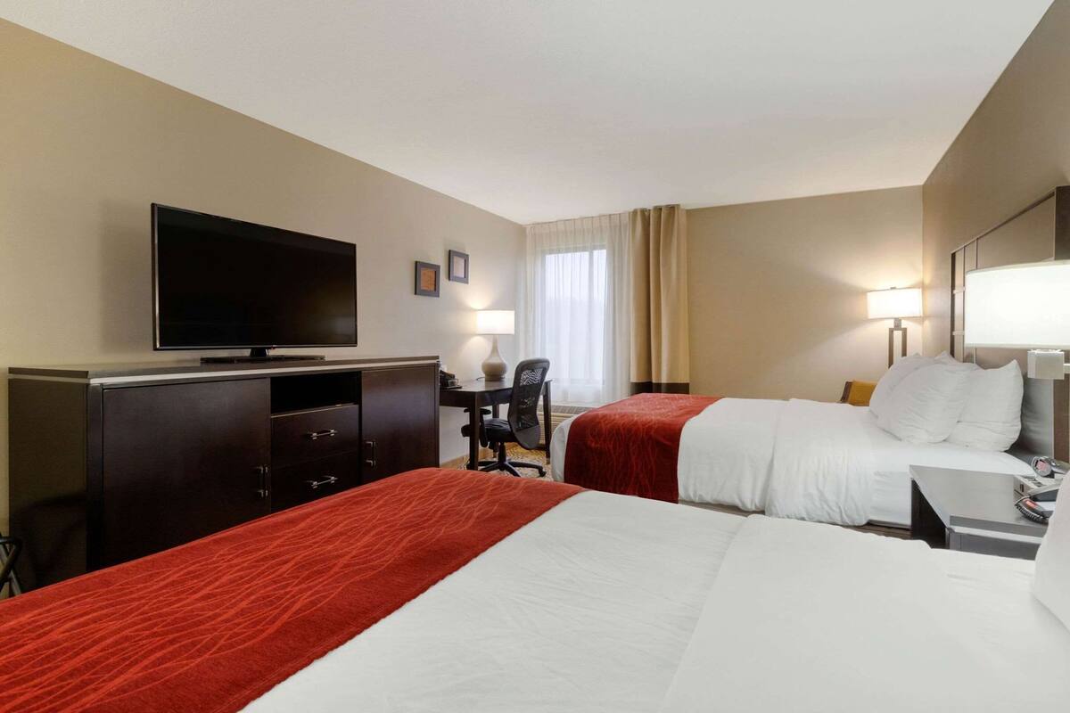 Une chambre d’hôtel avec deux lits, un bureau, une télévision et une chaise.