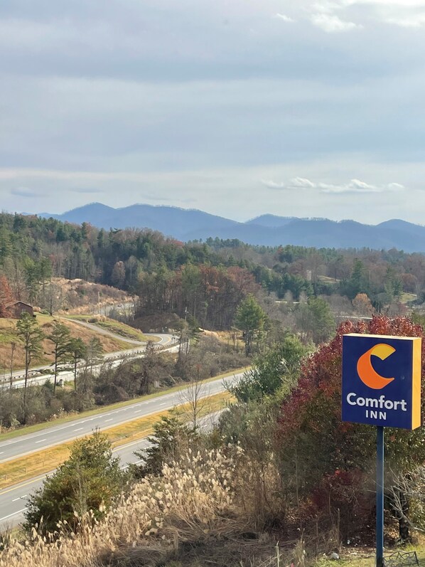 A Comfort Inn sign with a view of a highway and mountains in the background.