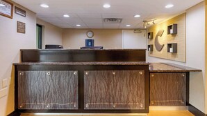 Un comptoir d’accueil avec une horloge, un ordinateur Dell et un élément décoratif fixé au mur.