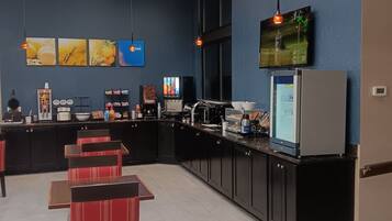 A modern restaurant with a counter, seating area, and kitchen.