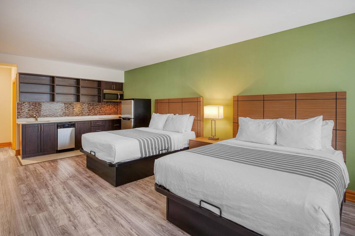 Ein Hotelzimmer mit zwei Betten, einer Küchenzeile und einer grünen Wand.