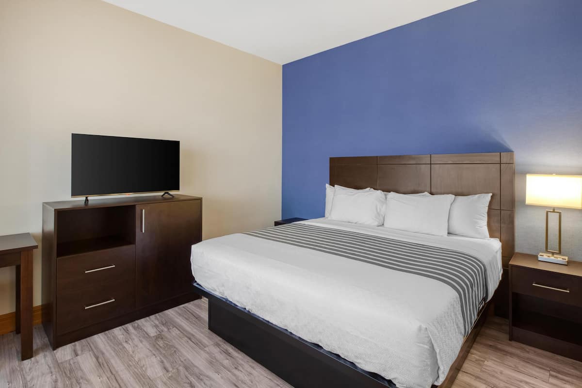 Ein Hotelzimmer mit Bett, Fernseher, Schreibtisch und Nachttisch.