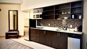 Une cuisine moderne avec des meubles de couleur bois foncé, un réfrigérateur en acier inoxydable, un four à micro-ondes encastré et un lave-vaisselle.