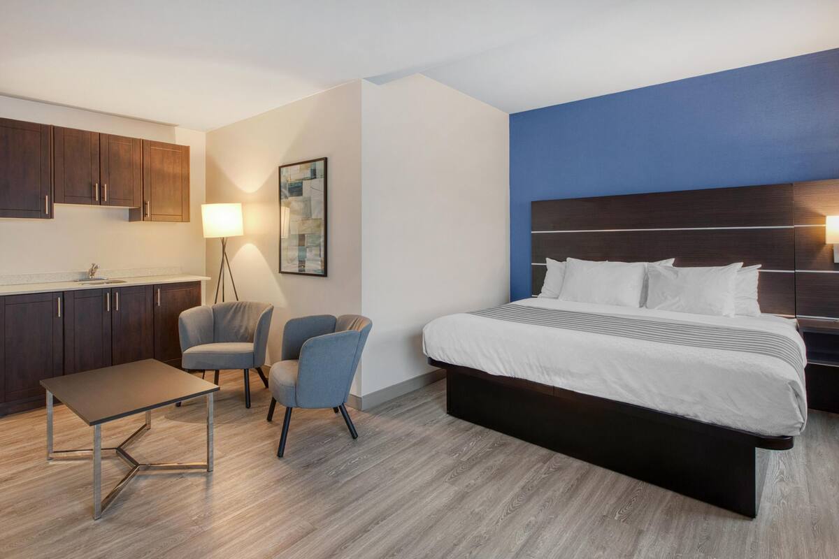 Ein Hotelzimmer mit Bett, Schreibtisch, Stuhl, Lampe und einem Bild an der Wand.