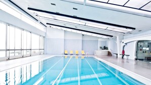 A large indoor swimming pool with clear blue water, yellow lounge chairs, and a modern ceiling design. - Golden Tulip Porto Gaia Hotel (Vila Nova de Gaia)