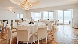 A spacious dining area with round tables, white chairs, and a large chandelier. - Golden Tulip Porto Gaia Hotel (Vila Nova de Gaia)