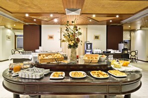 Disposição de buffet com diversos alimentos e um arranjo decorativo.