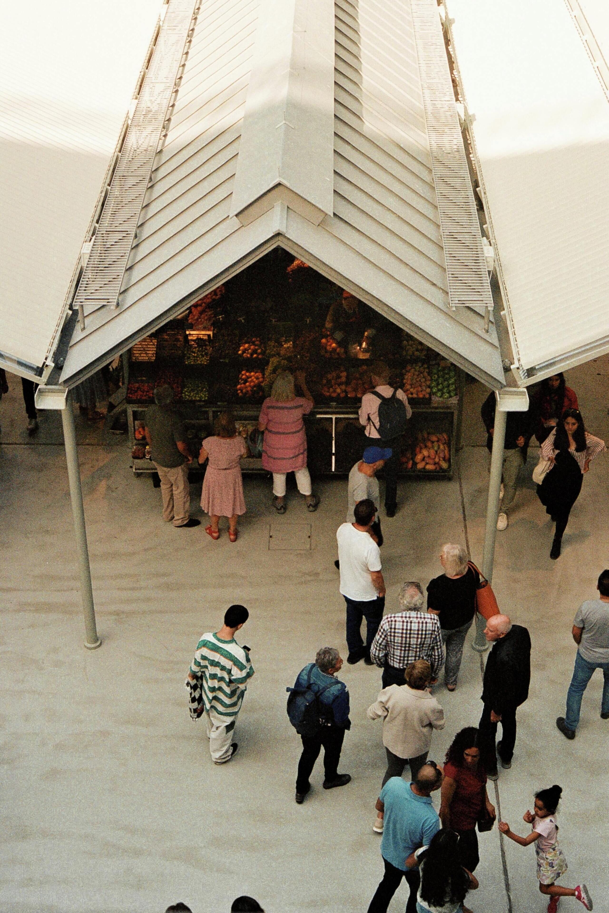 Un mercado al aire libre techado donde la gente compra.