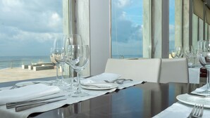 A dining table set with white tableware and wine glasses, overlooking a beach. - Golden Tulip Porto Gaia Hotel (Vila Nova de Gaia)