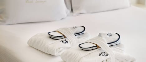 A neatly made bed with white linens and towels folded at the foot of the bed.