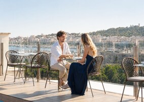 Una pareja cenando en una mesa al aire libre con vistas a la ciudad.