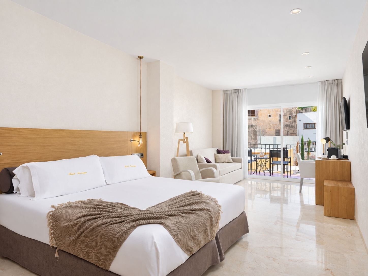 Une chambre d’hôtel équipée d’un lit, d’un bureau, d’une chaise, d’une lampe et offrant une vue sur l’extérieur.
