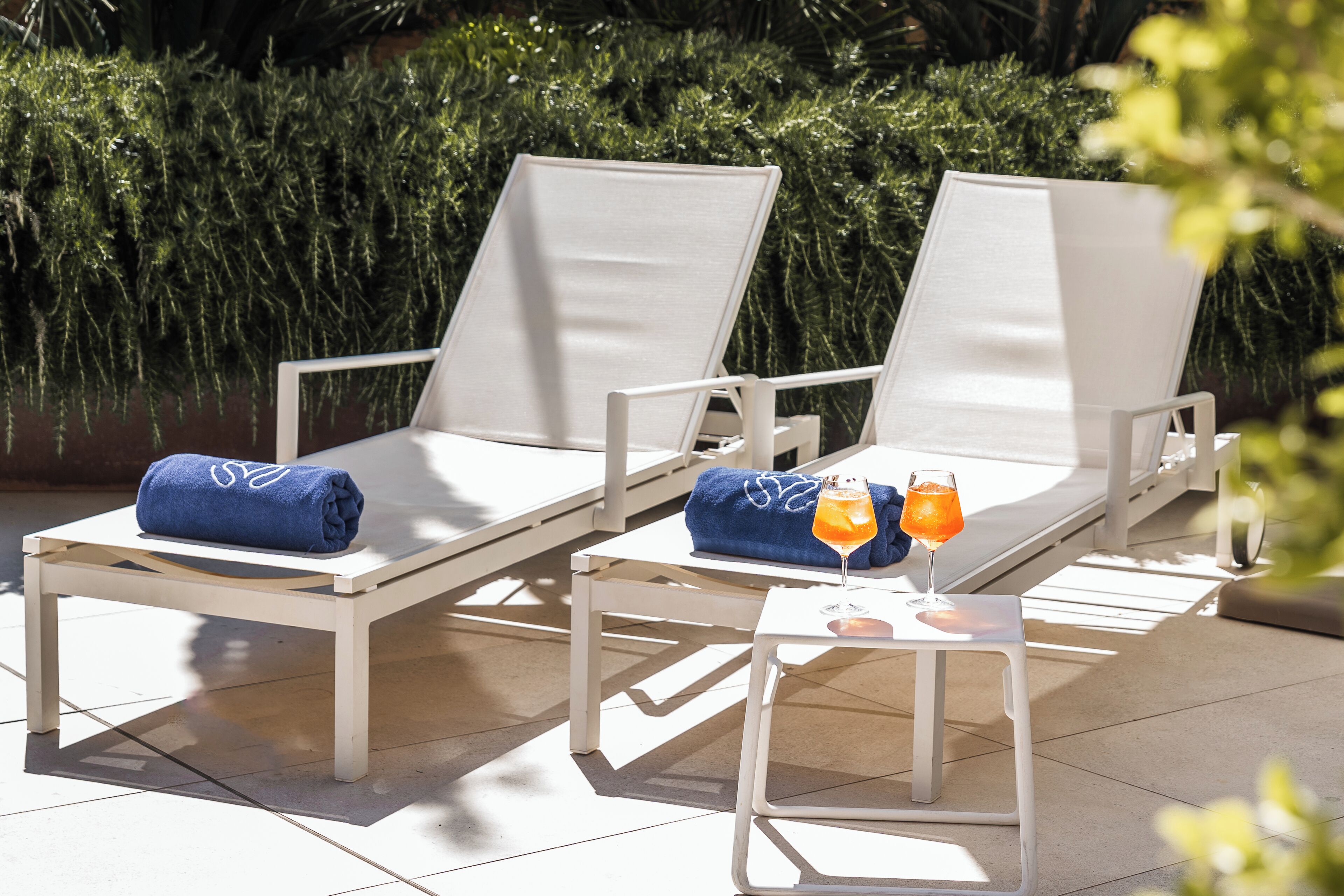 Deux chaises longues avec des serviettes, une petite table et une boisson.