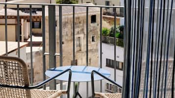 Un balcón con mesa y sillas, con vistas a un pueblo histórico y una torre de iglesia.