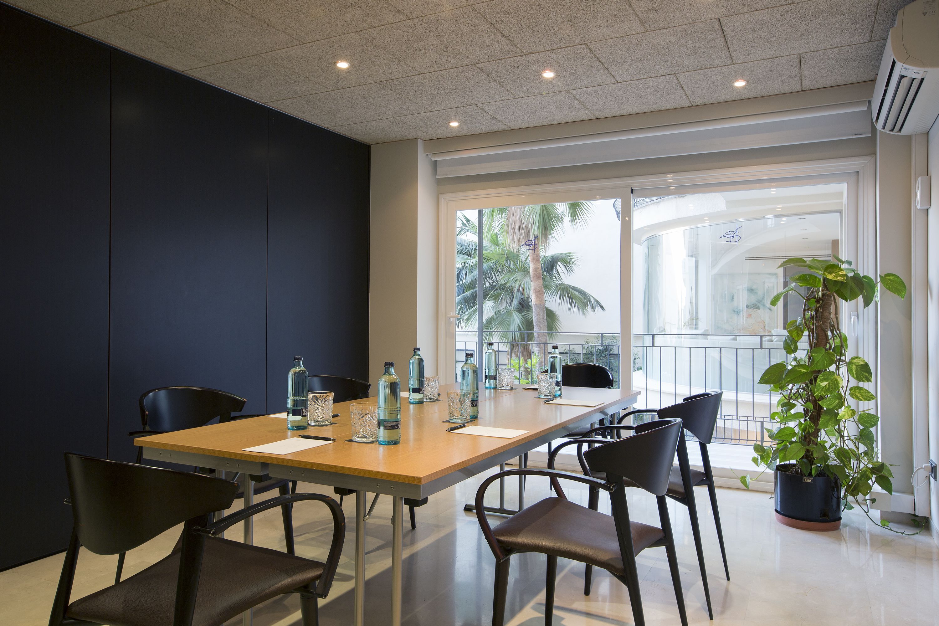Une salle de conférence avec une longue table, des chaises et une plante en pot.