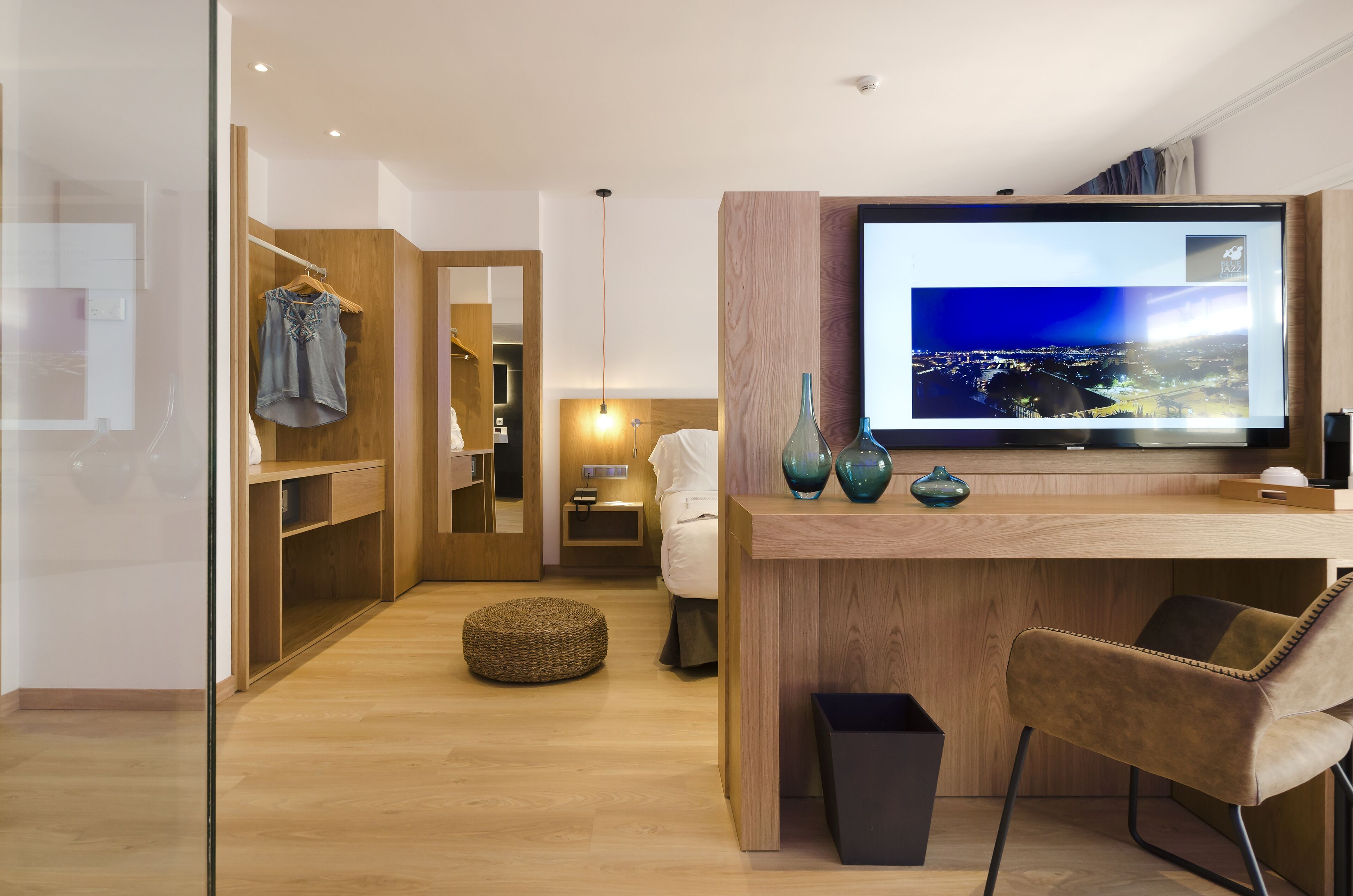 Una habitación de hotel moderna con un escritorio de madera, televisor y una zona de estar acogedora.