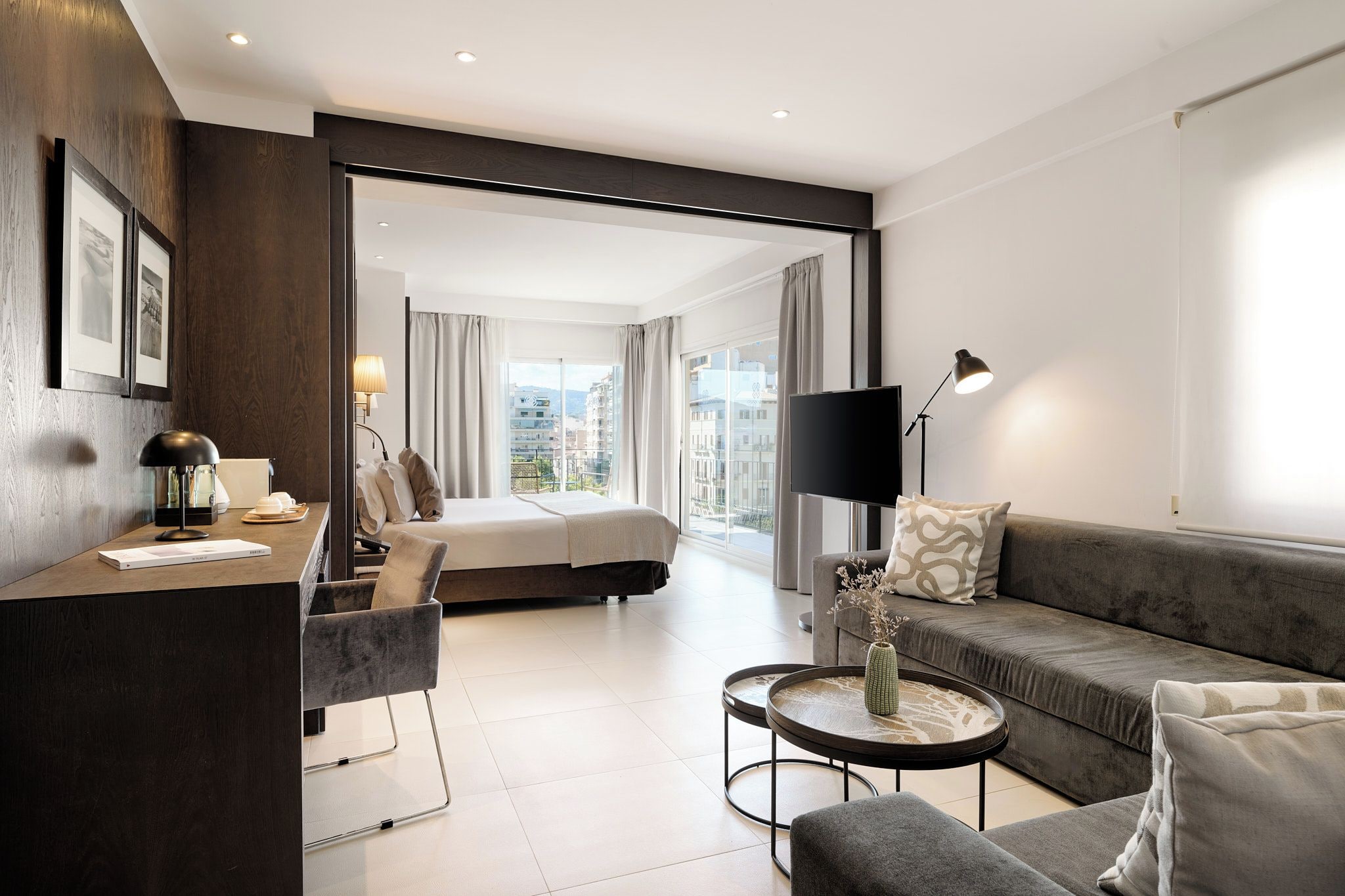 Una habitación de hotel moderna con cama, sofá, escritorio y una mesita de café.