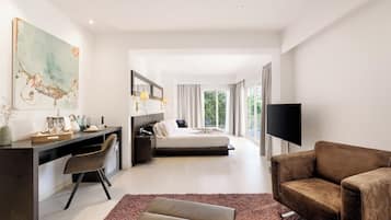Ein modernes Hotelzimmer mit Bett, Schreibtisch, Sessel, Fernseher und großem Fenster.