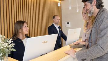 A reception desk with three ASUS laptops, a wooden panel wall, and a modern light fixture.