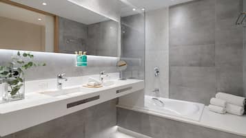 Un baño moderno con un espejo grande, dos lavamanos, una bañera y una ducha.