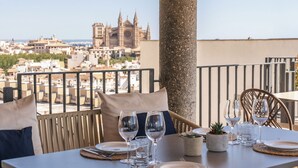 Mesa lista con platos, vasos y cubiertos, con vista a un paisaje urbano y arquitectura histórica.