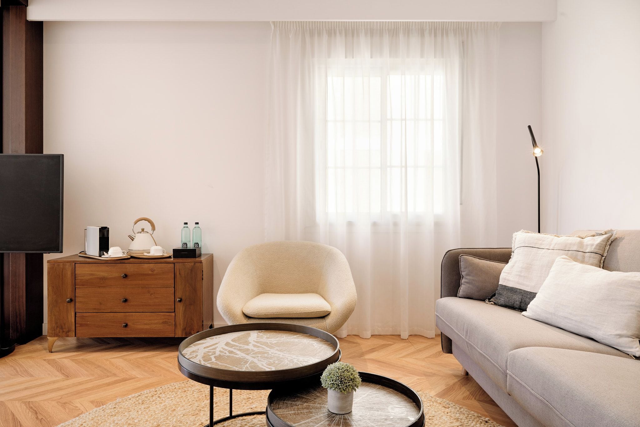 A modern living room with a sofa, armchair, coffee table, and a TV.