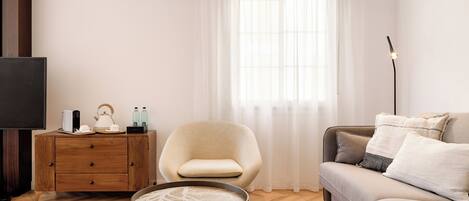 A modern living room with a sofa, armchair, coffee table, and a TV.