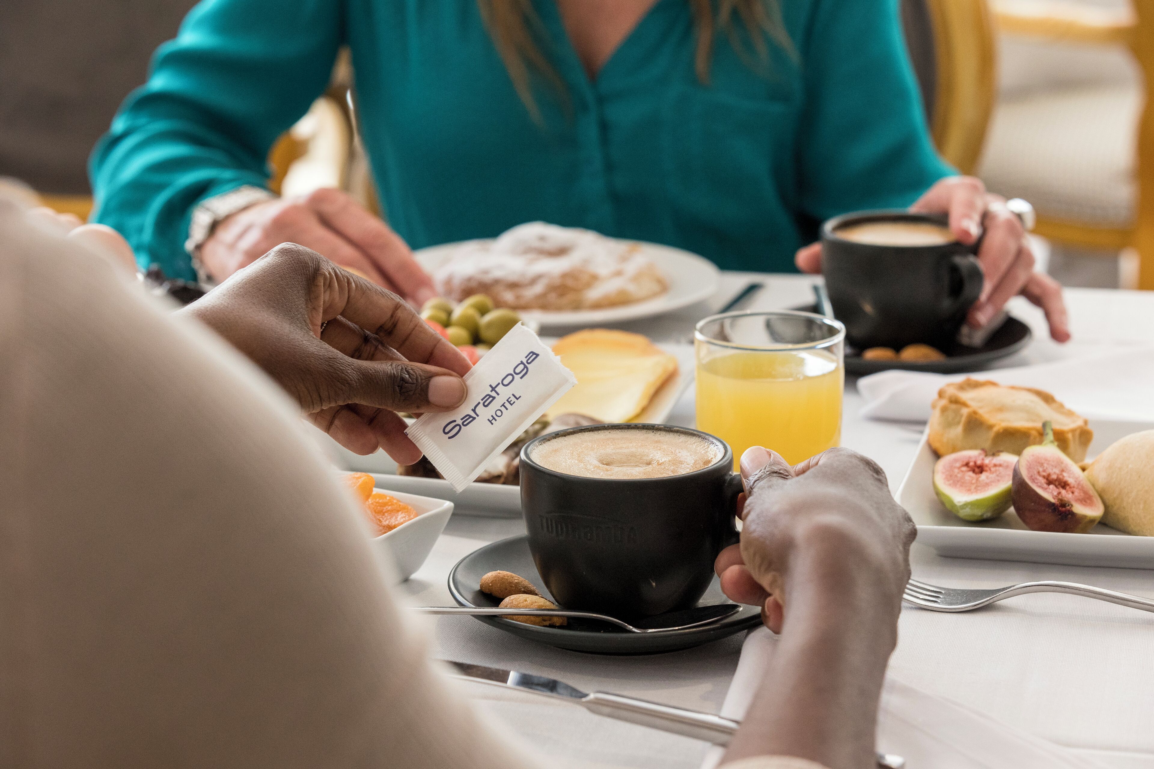 A breakfast setting with a coffee cup, a glass of orange juice, and a plate with pastries and fruit.