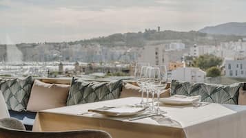 A dining area with a table set for two, overlooking a cityscape.
