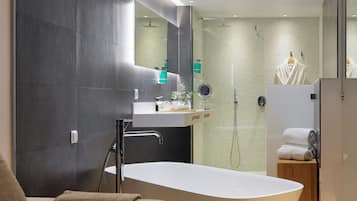 A modern bathroom with a freestanding bathtub, a vanity with a mirror, and a shower area.