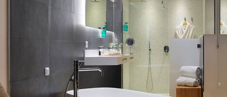 Un baño moderno con una bañera independiente, un tocador con espejo y una zona de ducha.