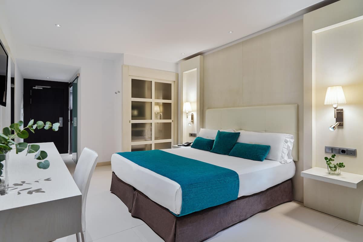 Een moderne hotelkamer met een groot bed, een bureau en een kledingkast.