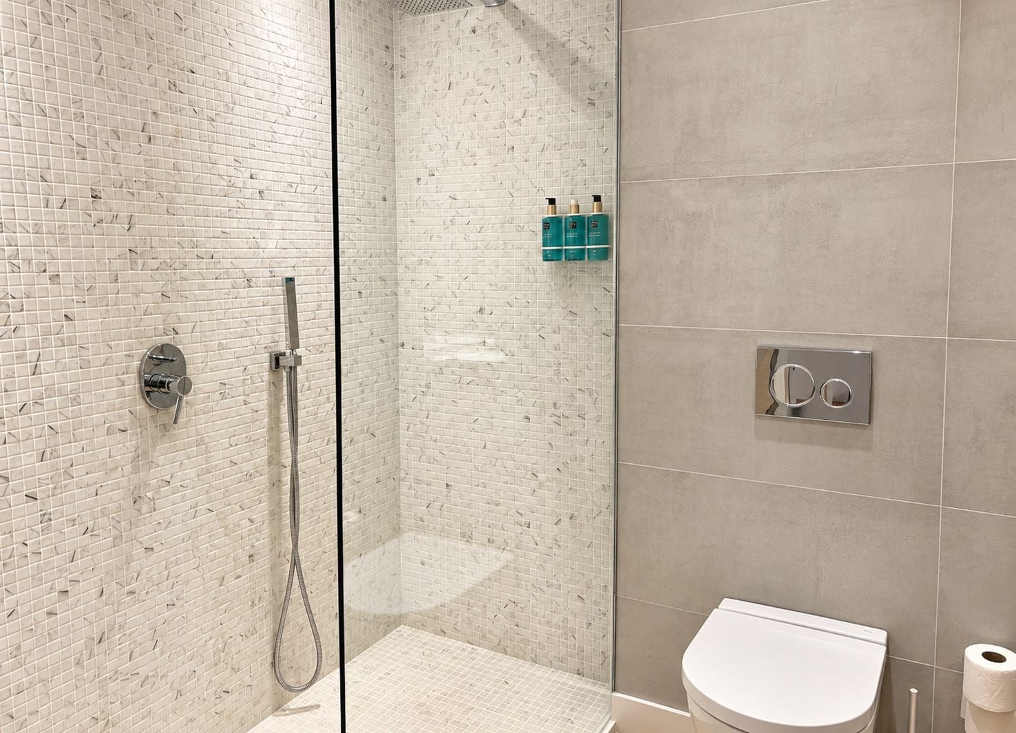 Un baño moderno con ducha envuelta en vidrio, inodoro y lavamanos.