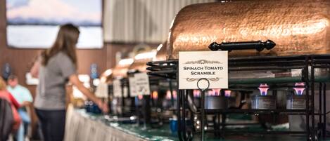 A buffet setup with labeled dishes, including a spinach tomato scramble.
