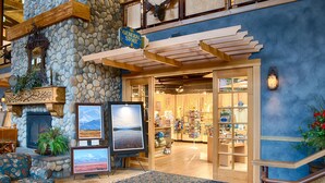 A lobby with a stone fireplace, a General Store sign, and a view of the store's interior. - Denali Princess Wilderness Lodge (Denali National Park)