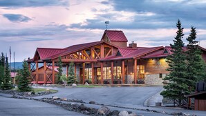 A lodge with a prominent red roof, wooden exterior, and a stone facade. - Denali Princess Wilderness Lodge (Denali National Park)