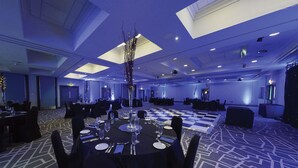 A banquet hall with tables set for dining, a central decorative vase, and a patterned carpet. - Village Hotel Leeds North (Leeds)