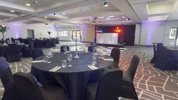 A conference room with round tables, black tablecloths, and chairs.