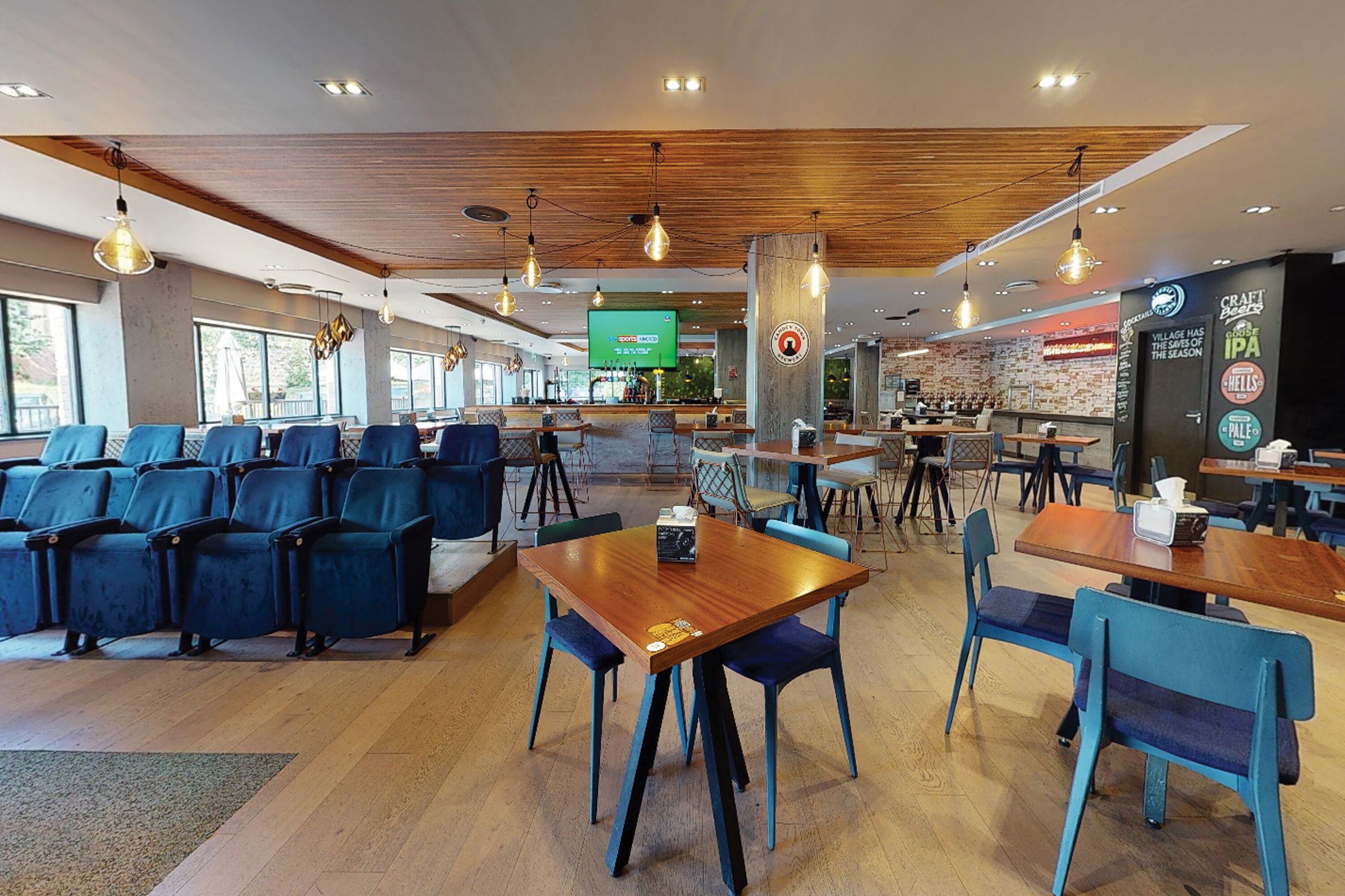 Un café spacieux doté de plusieurs espaces de détente, notamment des tables et des chaises, et d’un bar situé au fond de la salle.