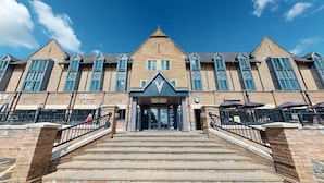 A building with a prominent 'VILLAGE' sign, a Starbucks, and a grill. - Village Hotel Leeds North (Leeds)