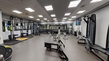 A gym with various weightlifting equipment, mirrors, and a clean, organized layout.