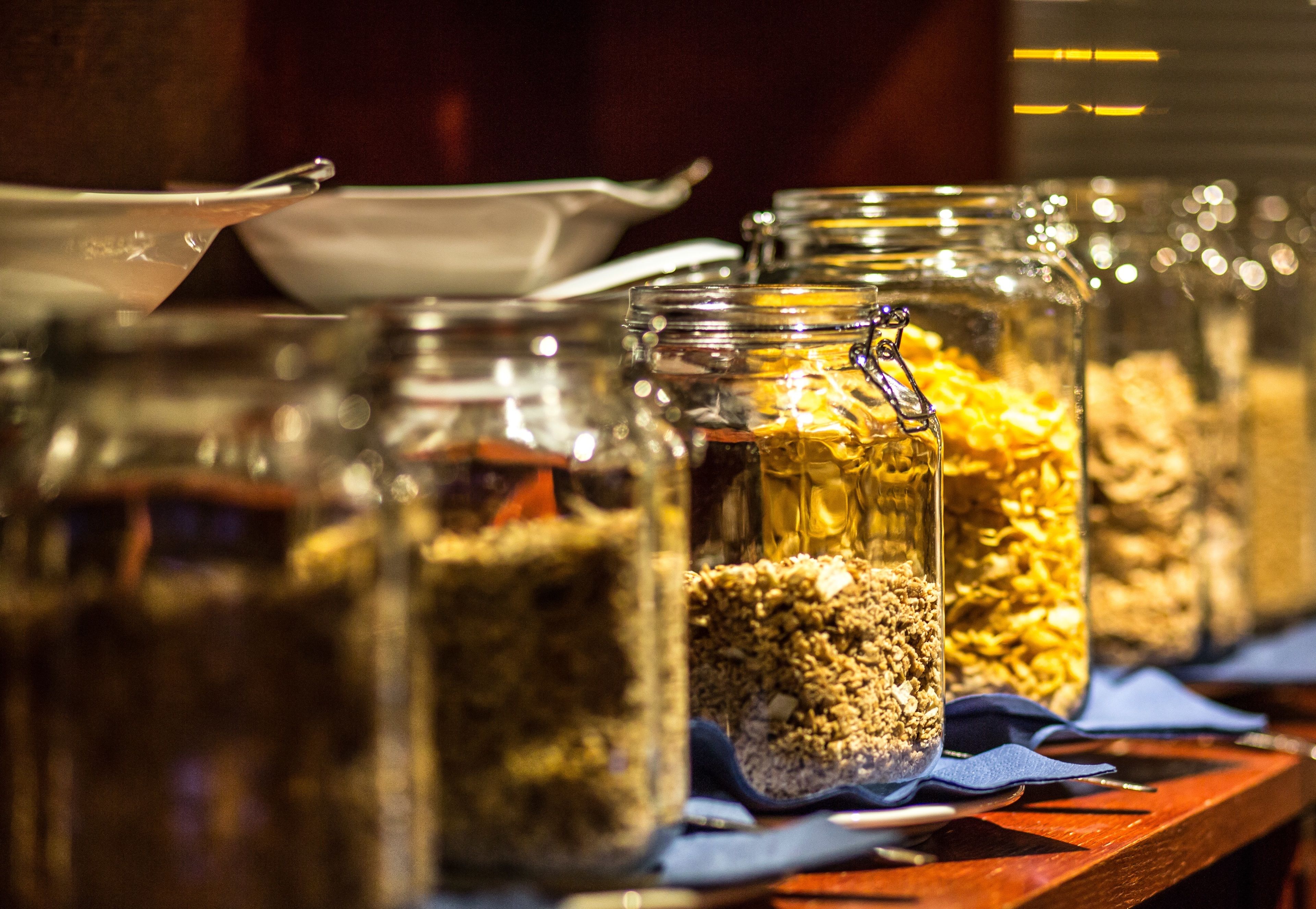 Diverses brosses de vidre amb granola damunt d'un taulell de fusta.