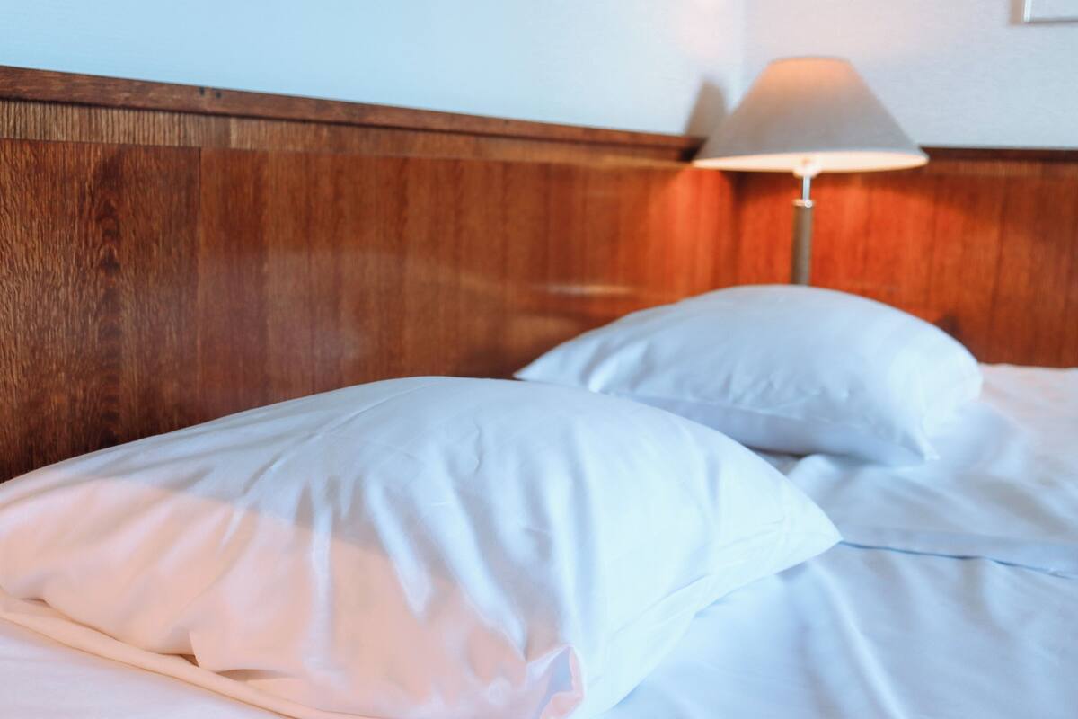 A bed with white bedding and a wooden headboard.