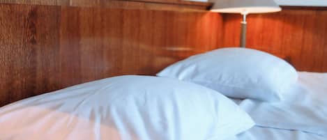 Una cama con ropa de cama blanca y cabecero de madera.