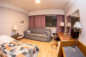 Relax in this inviting room with a comfortable sofa, neatly made bed, and large window offering a view.